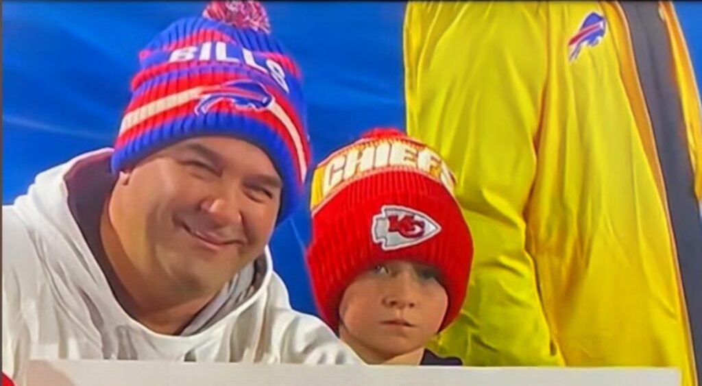 Buffalo Bills and Kansas City Chiefs fans posing with sign at game.