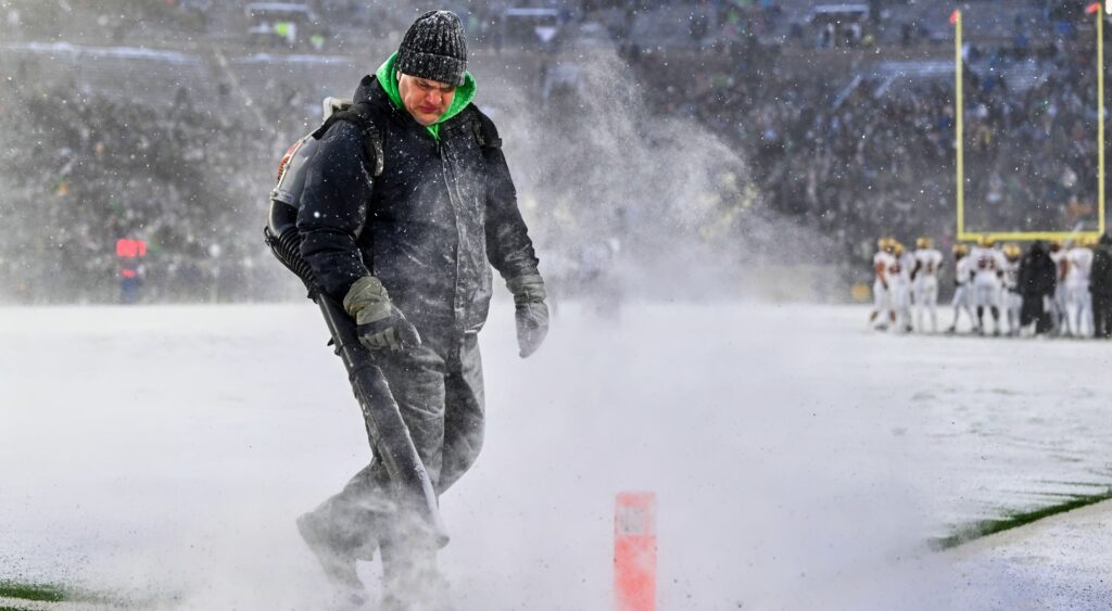 Worker cleaning snow at Notre Dame Fighting Irish stadium.