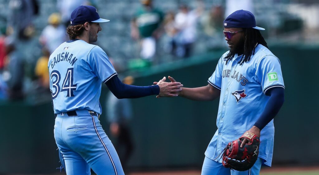 Kevin Gausman and Vladimir Guerrero Jr. shaking hands.