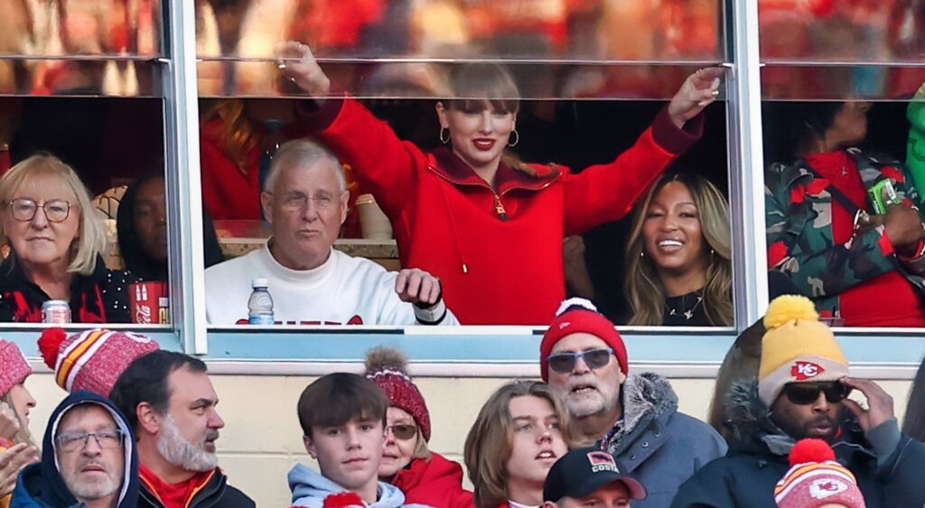 Taylor Swift with her hands up in suite