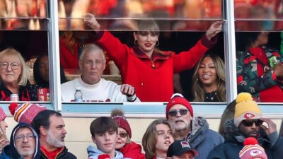 Taylor Swift with her hands up in suite