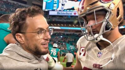 Mike McDaniel and Nick Bosa speaking on the field