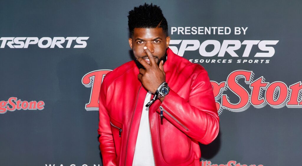 Emmanuel Acho posing in red jacket