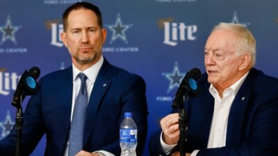 Brian Schottenheimer sitting next to Jerry Jones