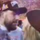 Travis Kelce and Taylor Swift looking at each other before a kiss