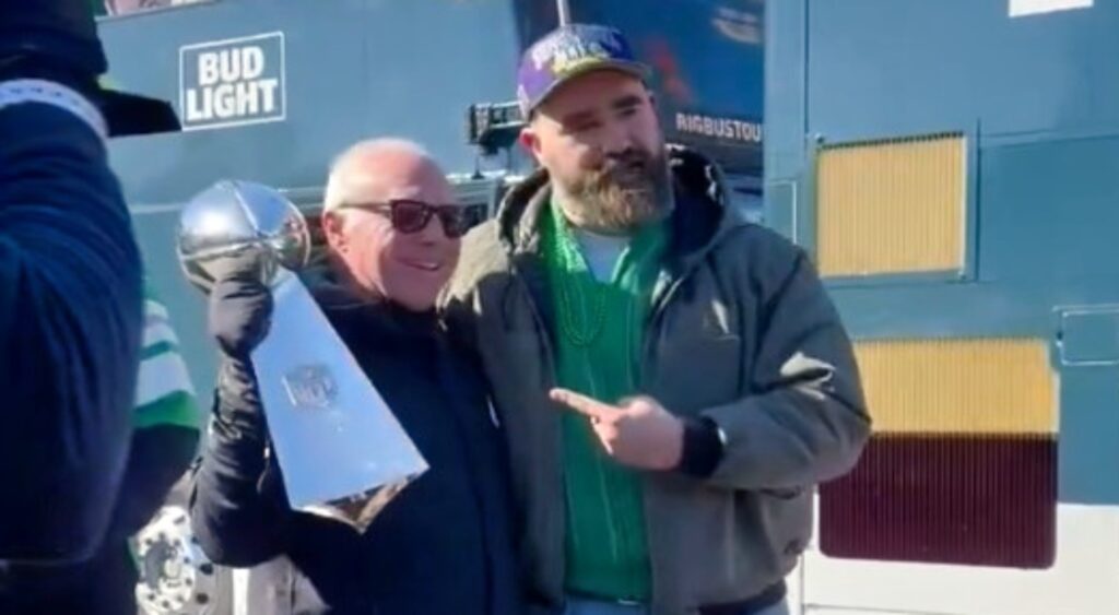 Jeffrey Lurie and Jason Kelce holding Super Bowl trophy.