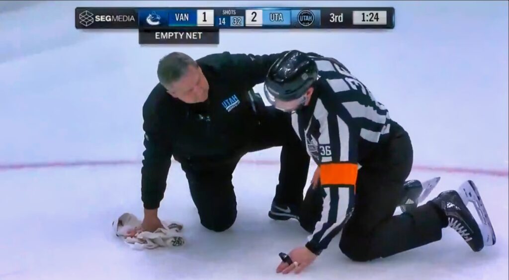 NHL referee Justin Kea (reacts after being hit by puck.